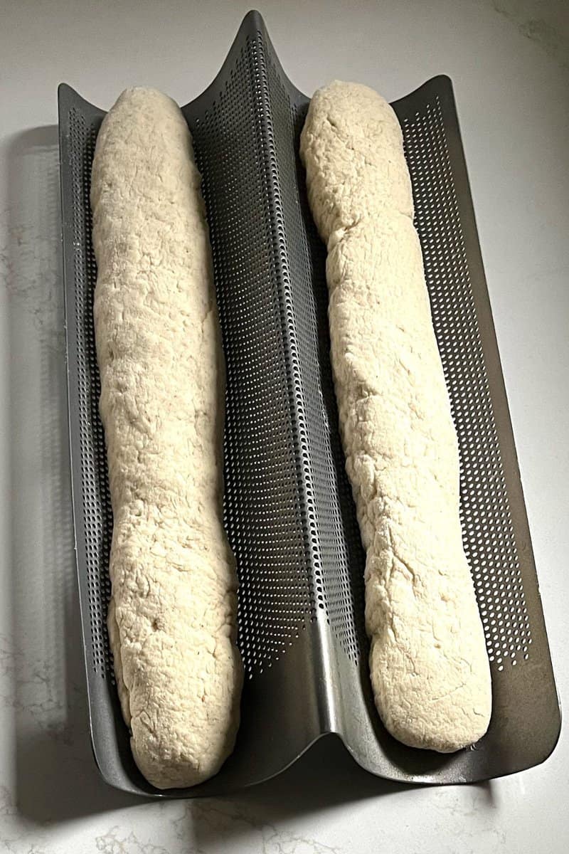 Fresh homemade gluten-free bread dough placed in a perforated bread proofing basket for baking.