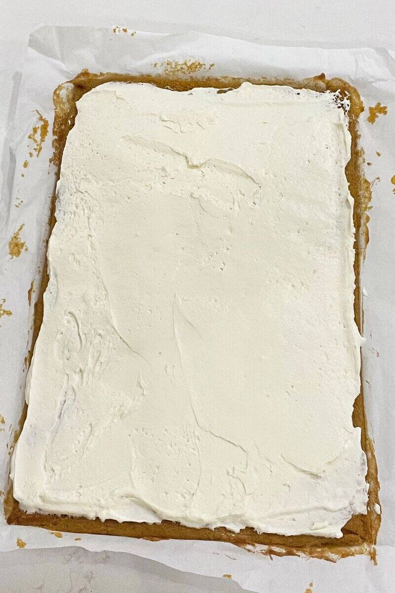 cream cheese frosting spread over baked cake in flat pan.