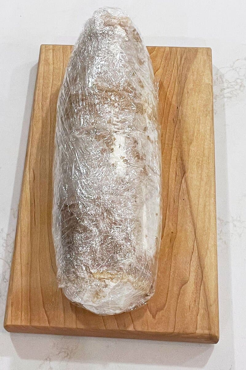 roll of cake wrapped tightly in plastic wrap.