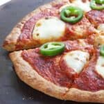 half sliced gluten-free pizza with tomato sauce, cheese, and pepper rings.