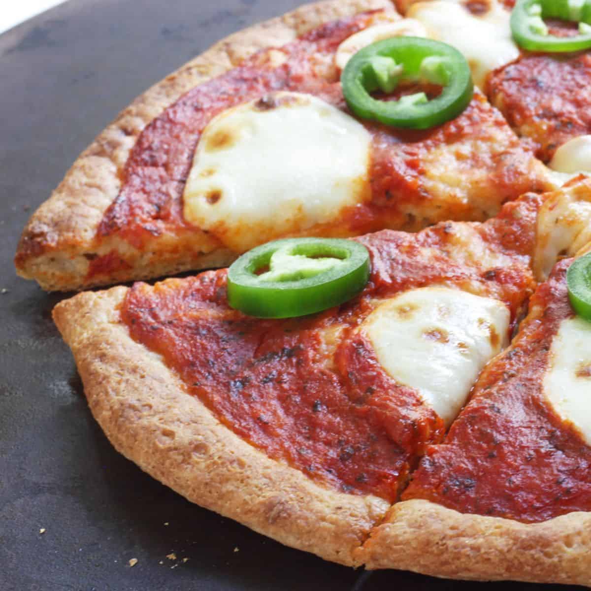 half sliced gluten-free pizza with tomato sauce, cheese, and pepper rings.