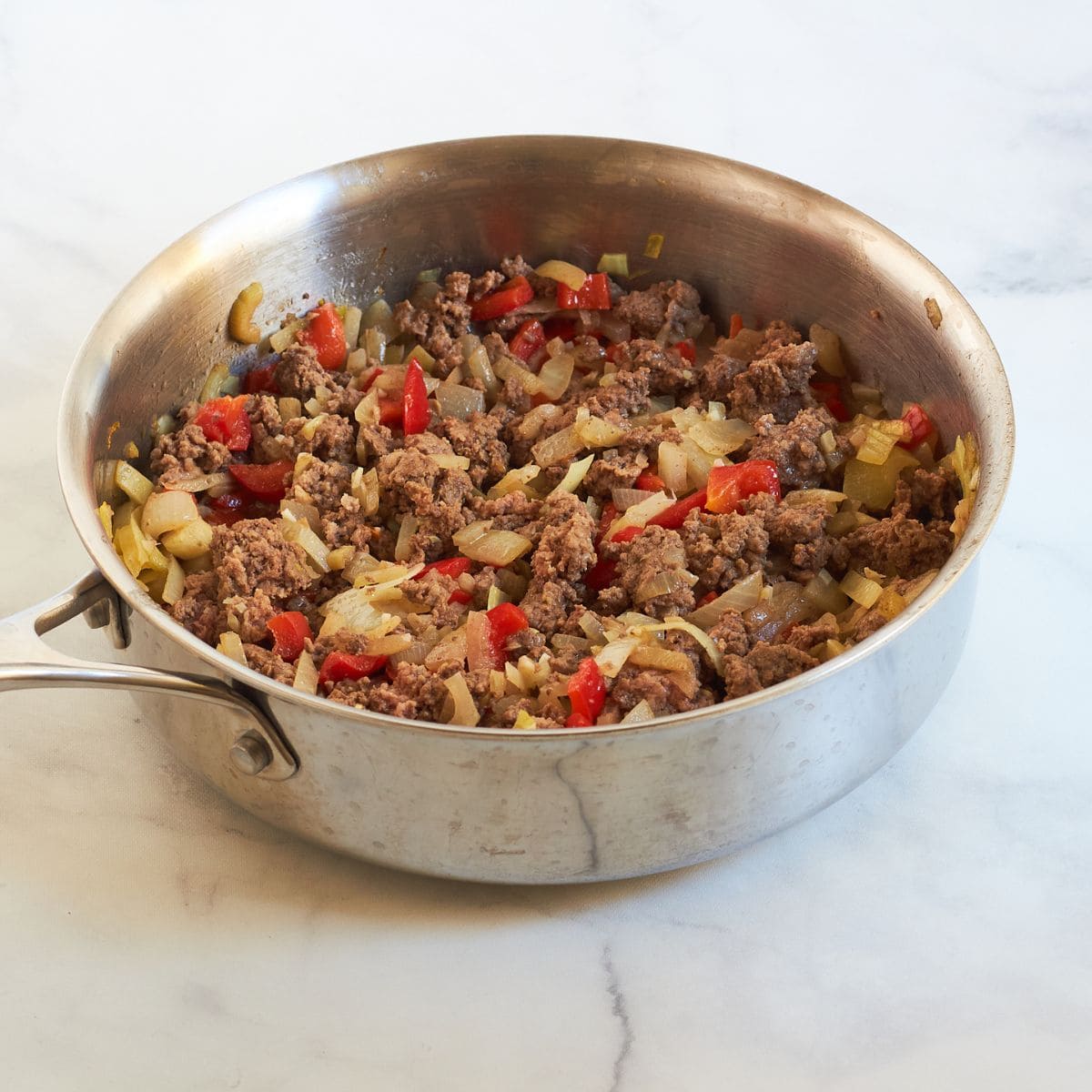 chopped onions, red bell pepper, and ground beef cooked in a stainless steel skiller.