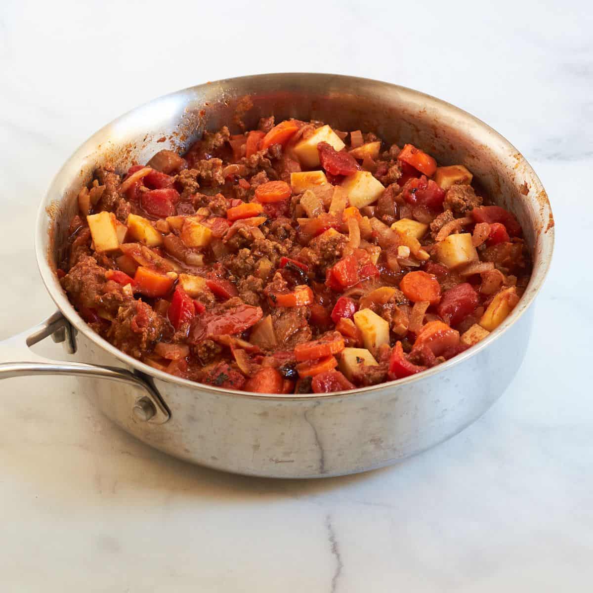 chopped vegetables and tomatoes with ground beef in skillet.