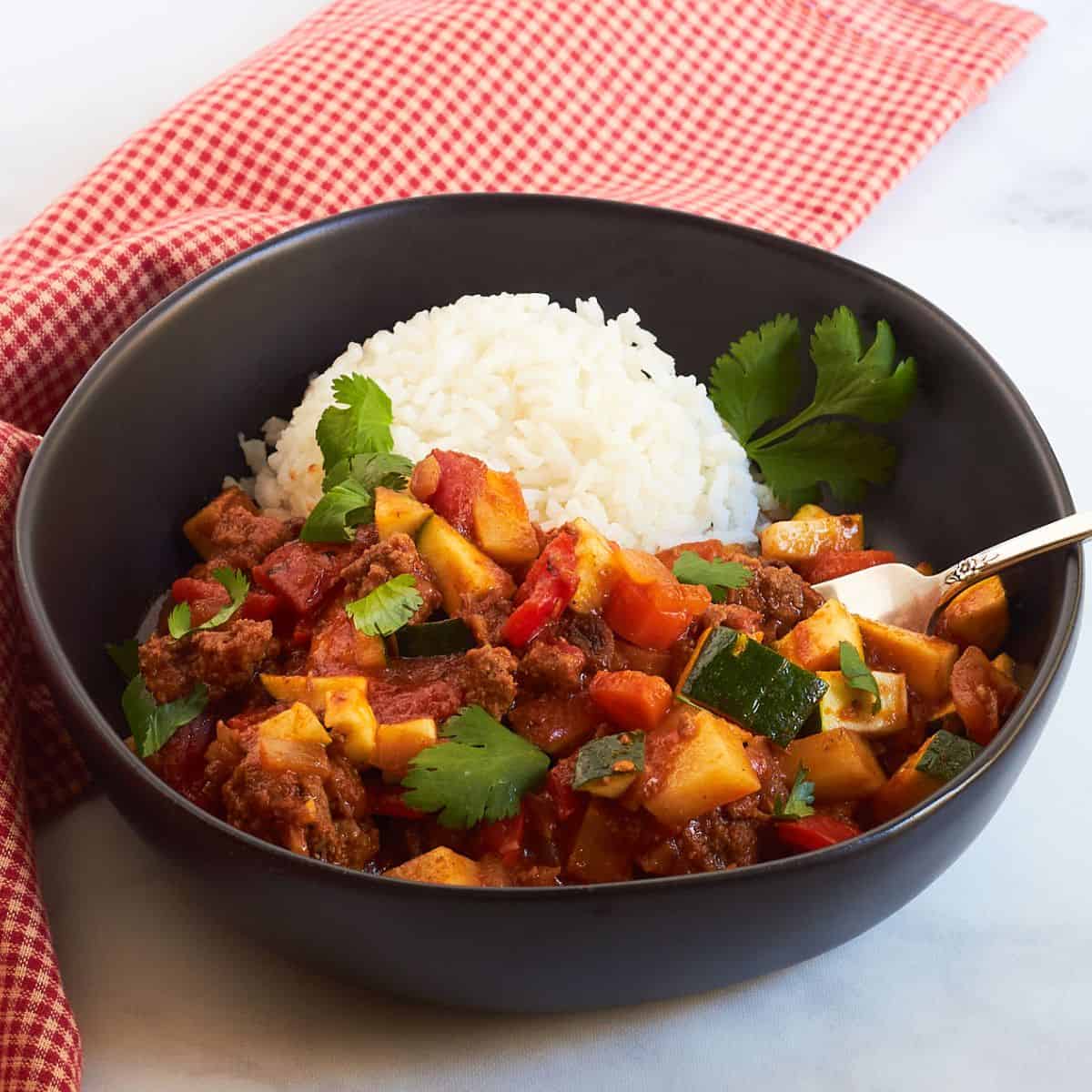 cuban picadillo served in black bowl with rice.