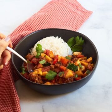 cuban picadillo in a black bowl with rice.