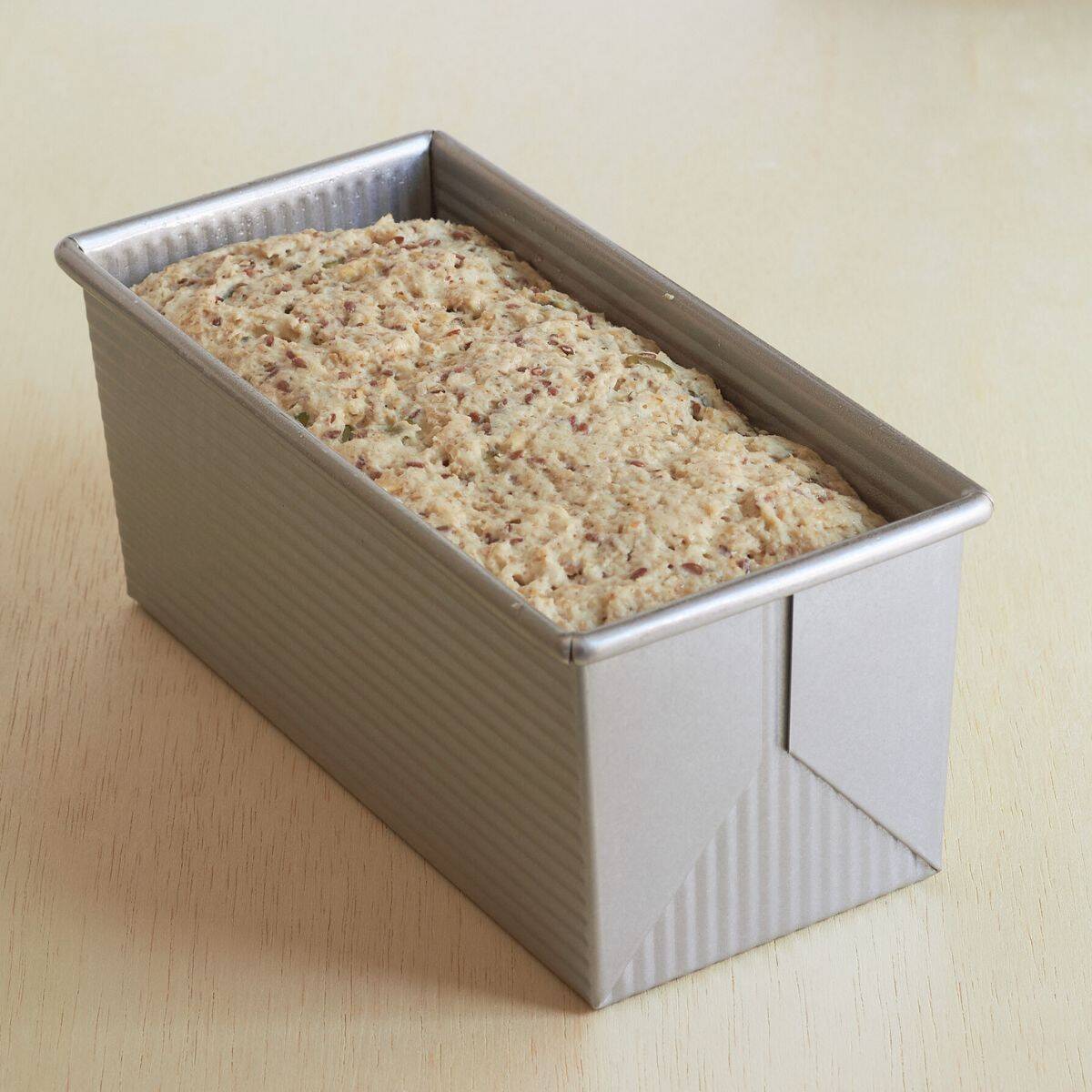moist, seeded batter risen near to the top of metal bread pan.