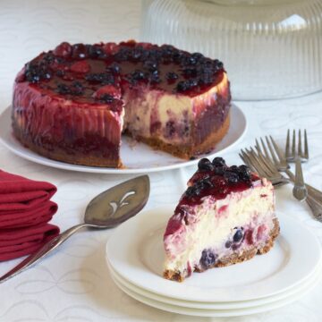 mixed berry cheesecake with a single slice served, on white plates.