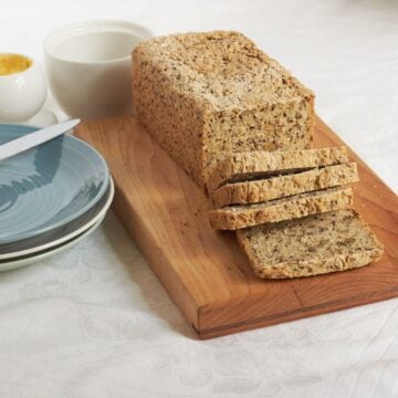 partially sliced gluten-free seed bread on a wooden board.