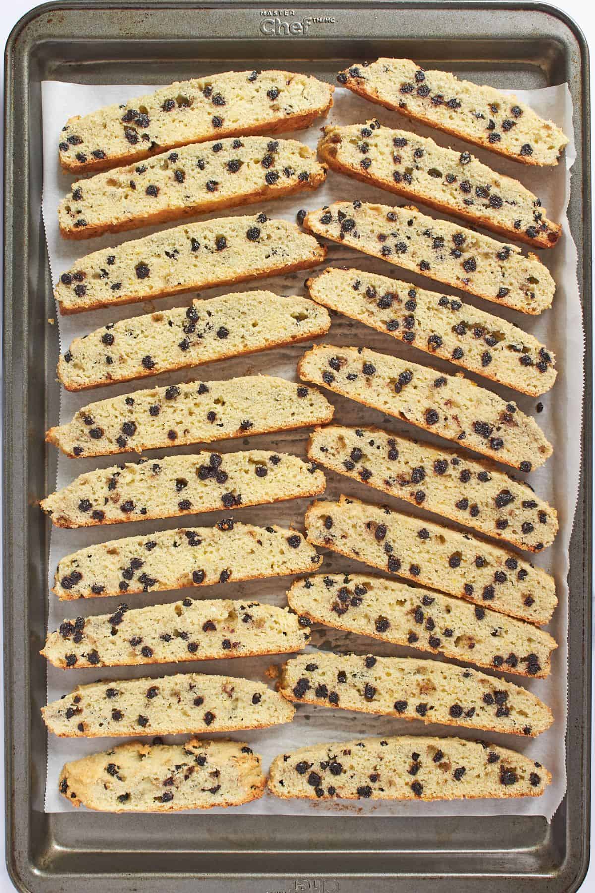 sliced biscotti arranged on parchment-lined tray for baking