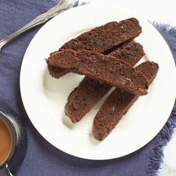 gluten-free chocolate biscotti on white plate on blue napkin.