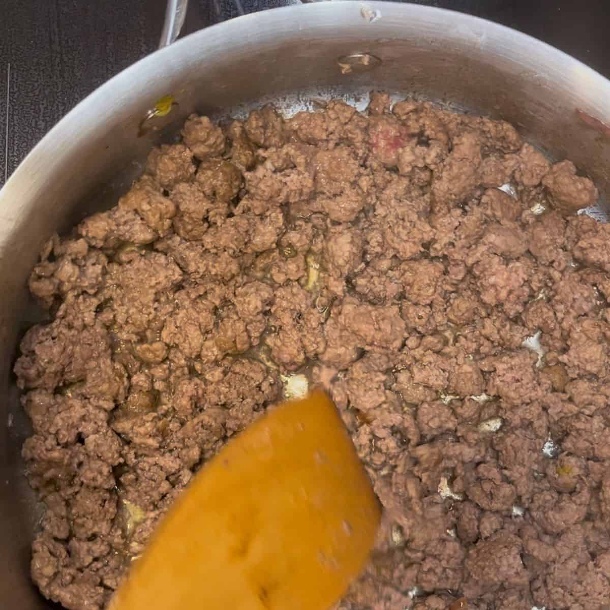 ground beef browning in a frying pan.