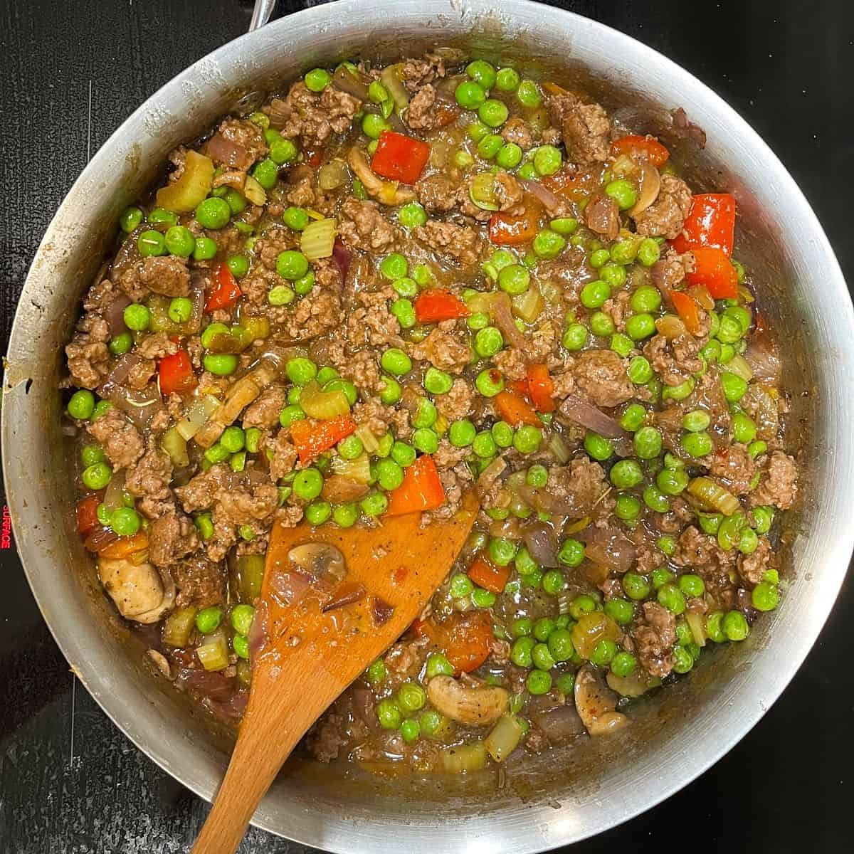 green peas with vegetables, ground beef, and sauce in pan.