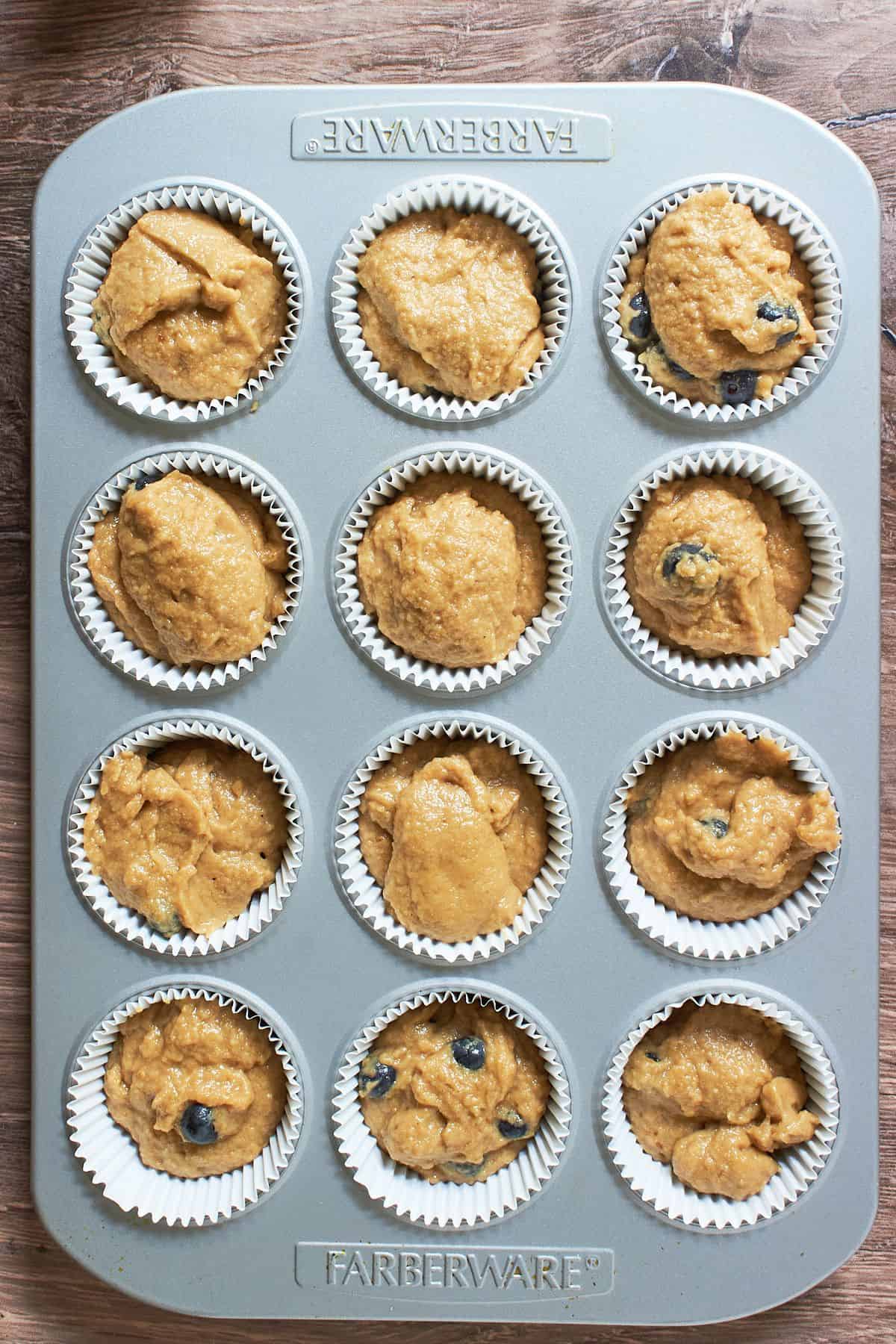 raw muffin batter in 12-cup tin with parchment paper liners.