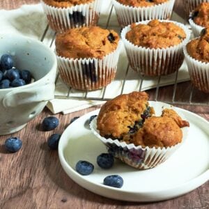 gluten-free blueberry muffins broken open on white plate.