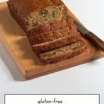 loaf of sliced gluten-free banana bread on wooden cutting board.
