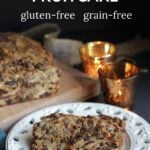 slices of gluten-free fruitcake on a white Christmas plate by glowing candles.