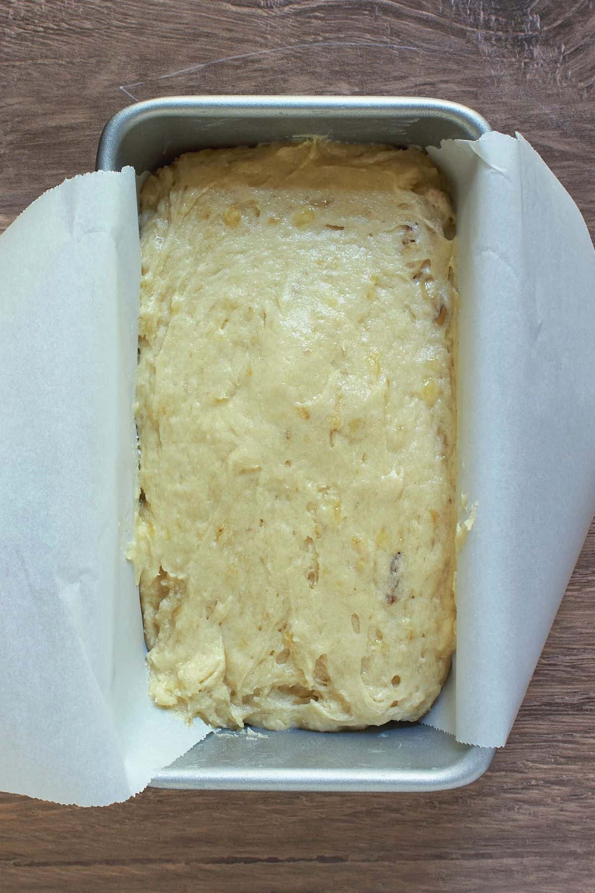 gluten-free banana bread batter in parchment-lined loaf pan.